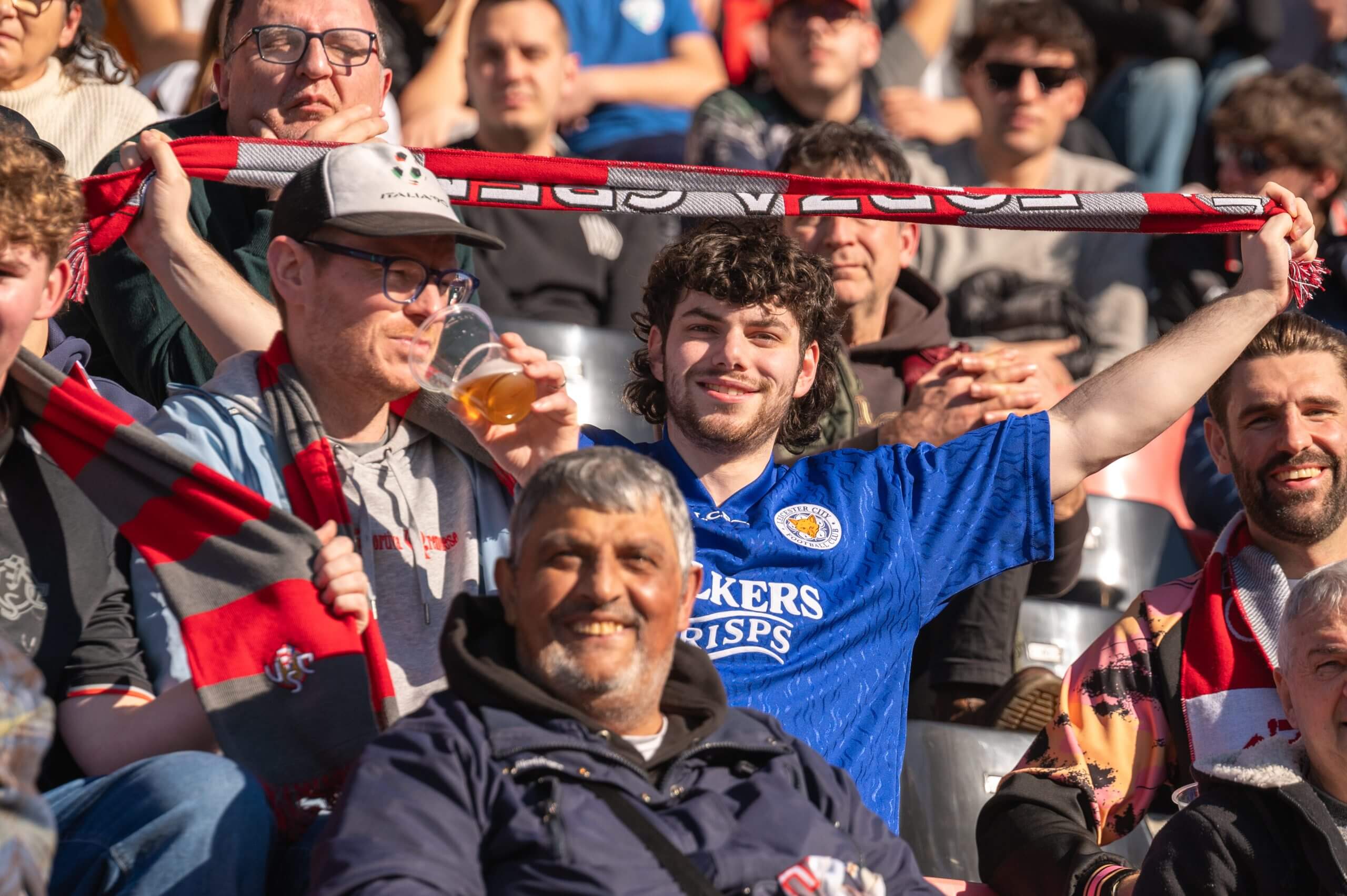 El partidario de Leicester, Dan Atkinson, sostiene una bufanda cremonese mientras Ric Flair bebe una pinta en las gradas.