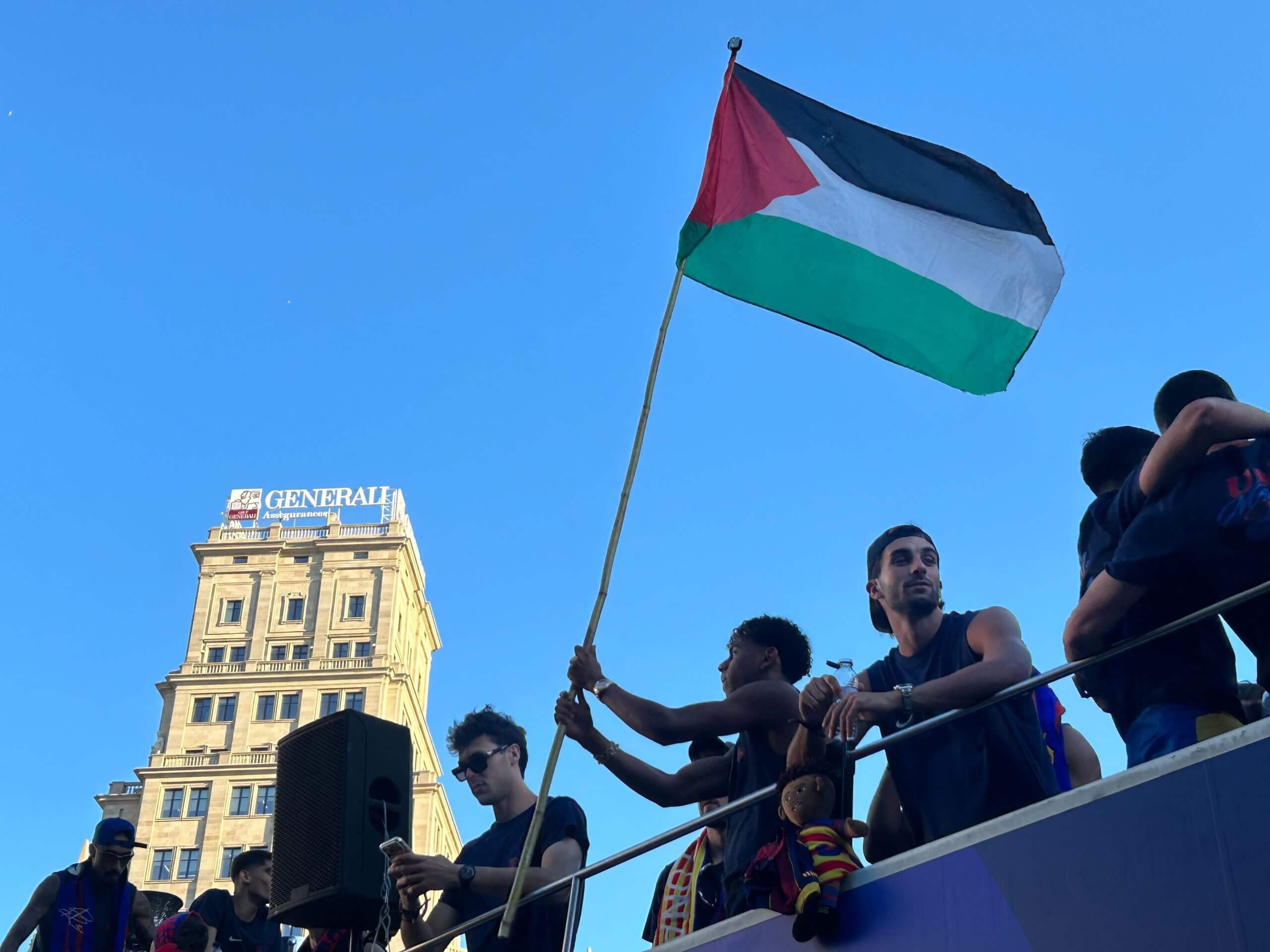 Yamal sostiene un asta de bandera palestina en el piso superior del autobús junto a sus compañeros del Barcelona.