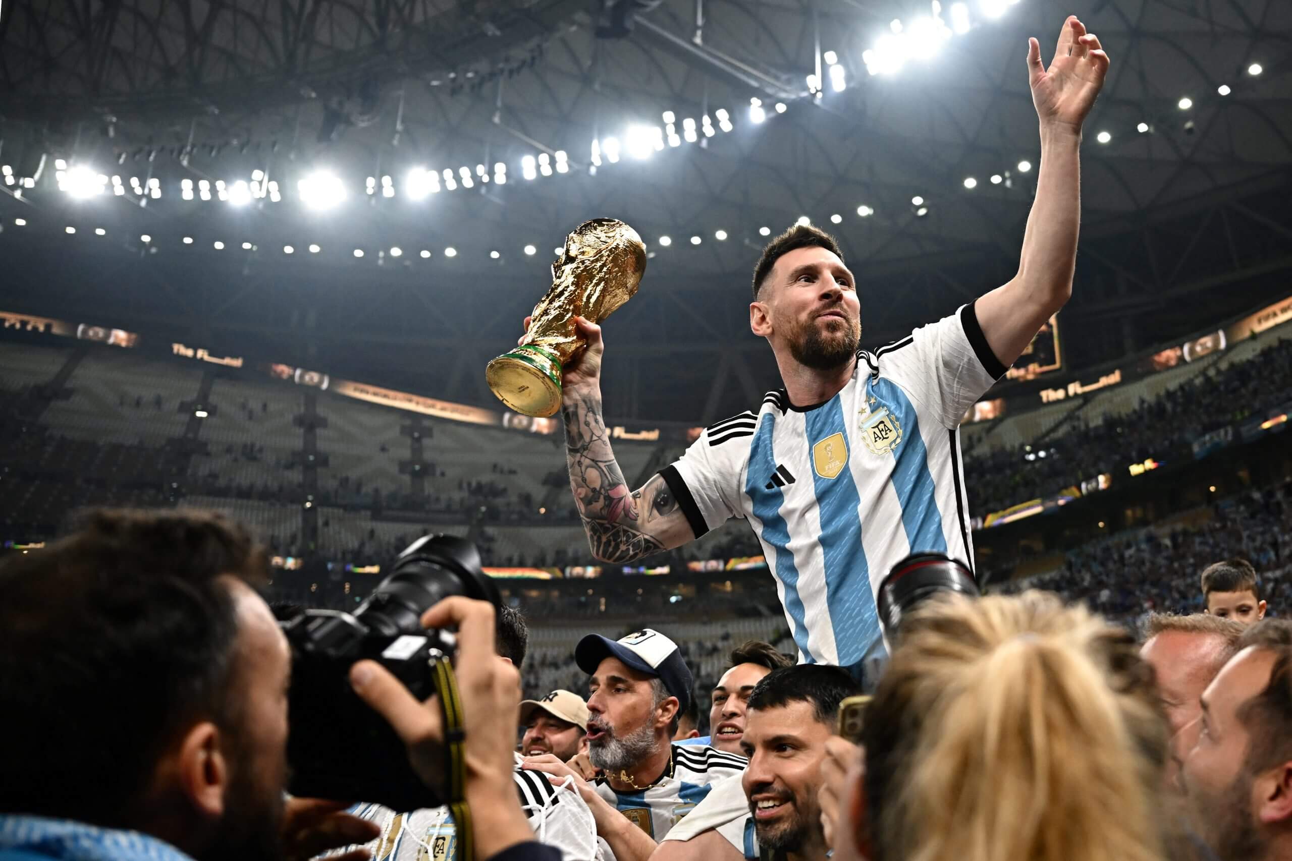 Argentina's Lionel Messi holds the World Cup following Argentina's victory over France at Lusail Stadium. He is on Sergio Aguero’s shoulders and all cameras and lights are on him