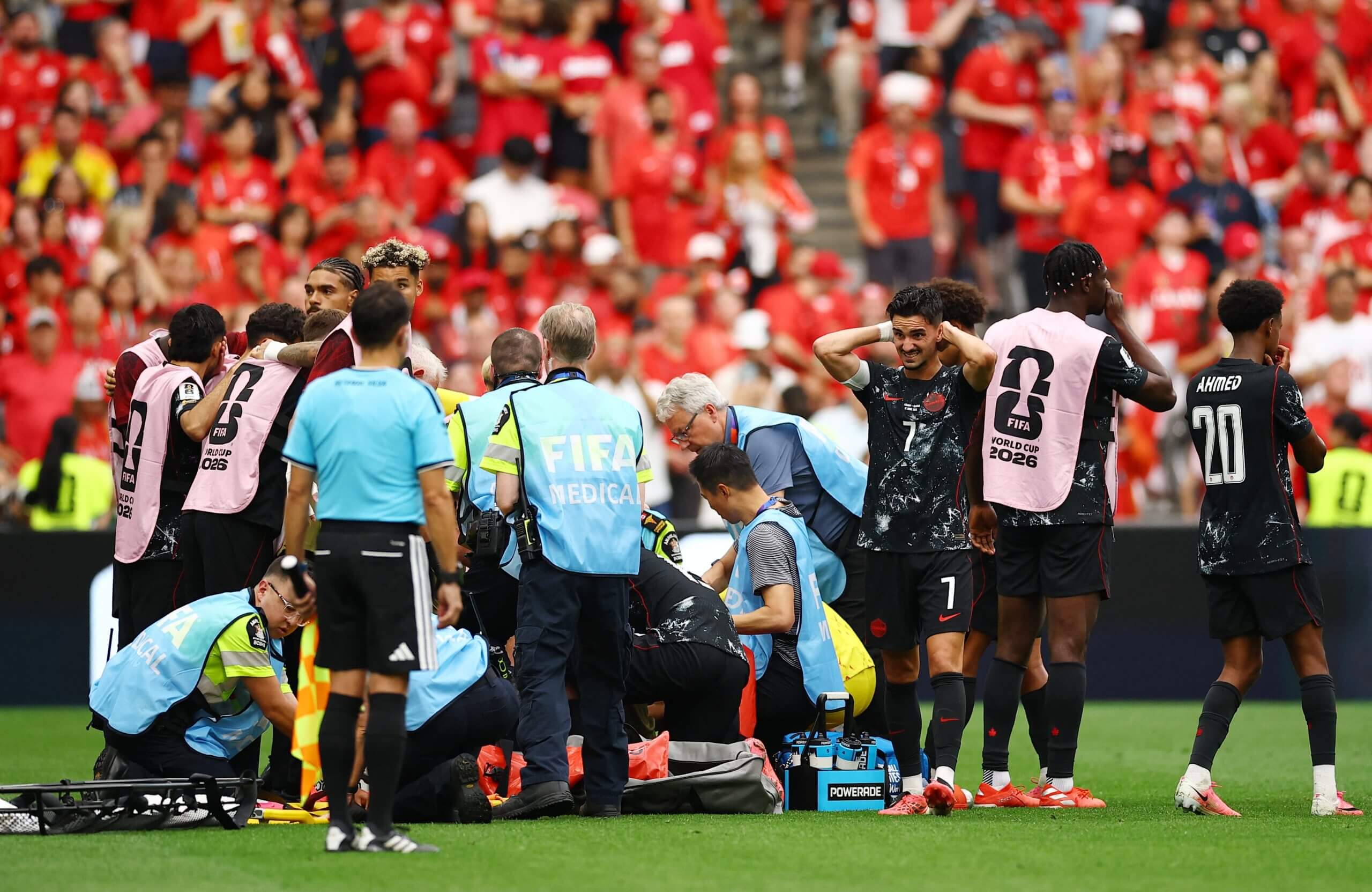 Los jugadores de Canadá parecen angustiados mientras el personal médico y los jugadores se reúnen alrededor de Kone (no visible) en una camilla.