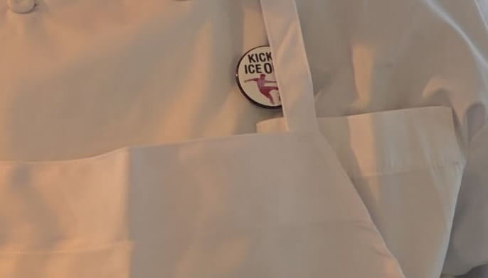 Foto de primer plano de una insignia de Kick Ice Out en un empleado del SoFi Stadium.