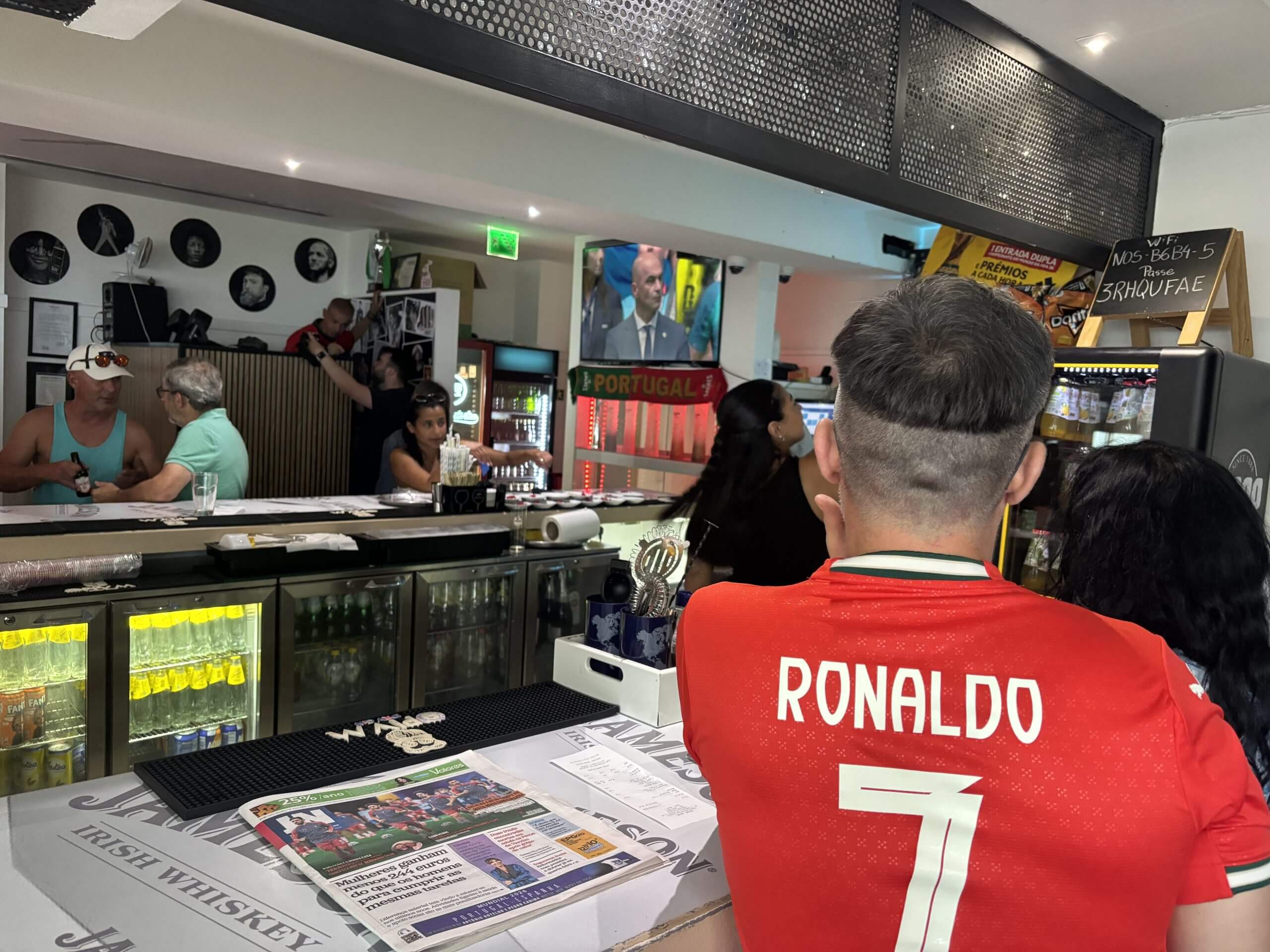 Varios clientes sentados alrededor de la barra del Bar Que? en Gales antes del inicio del partido