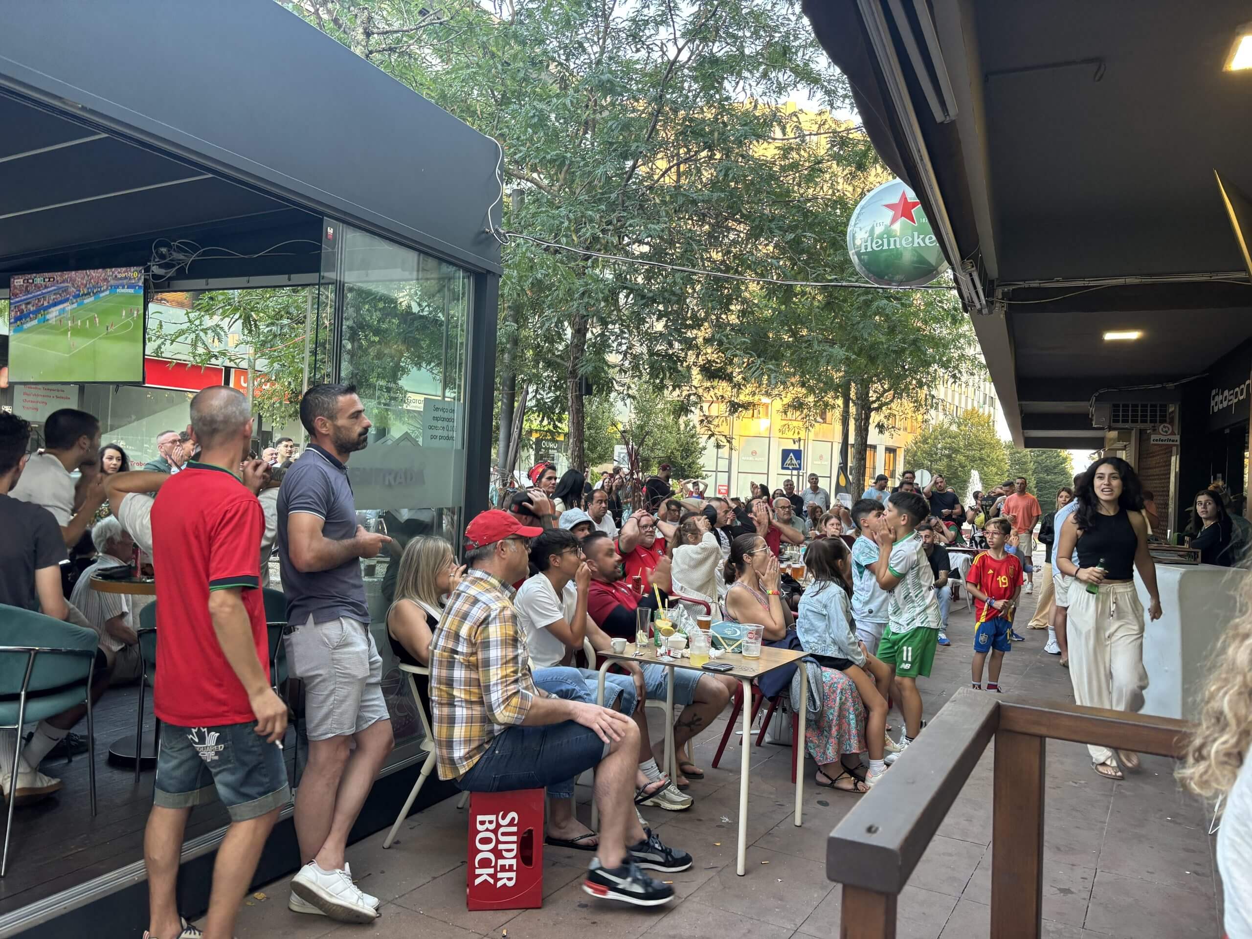 Vista del Que Bar: decenas de aficionados se sientan y miran el partido.