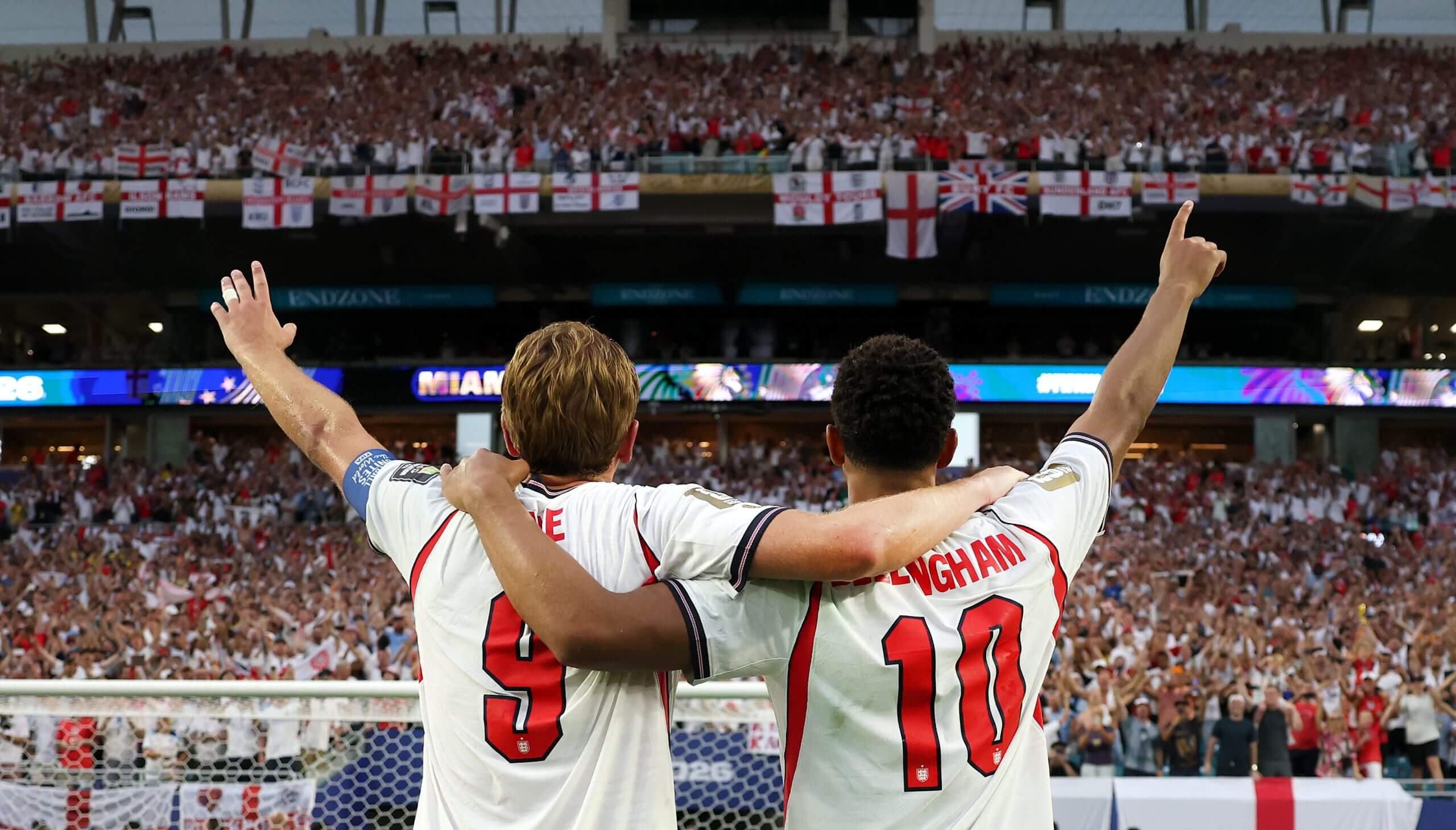 Harry Kane y Jude Bellingham levantan una mano cada uno mientras dirigen a los aficionados ingleses a una versión posterior al partido del Wonderwall en Miami.
